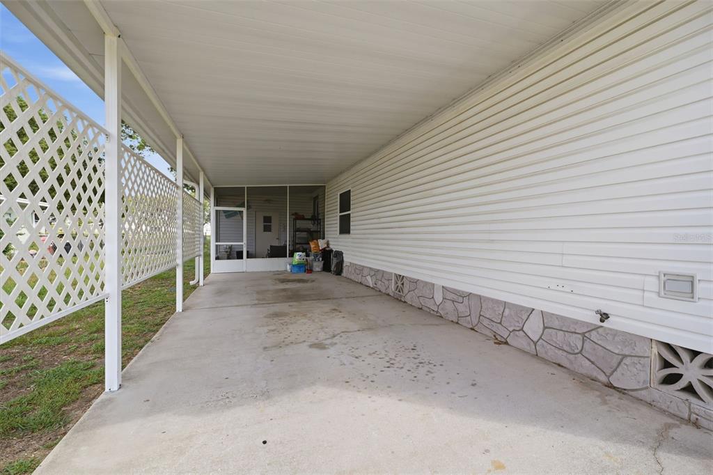 A concrete carport with a white lattice screen and a screened-in porch entrance — 15439 BROOKRIDGE BOULEVARD, BROOKSVILLE, FL