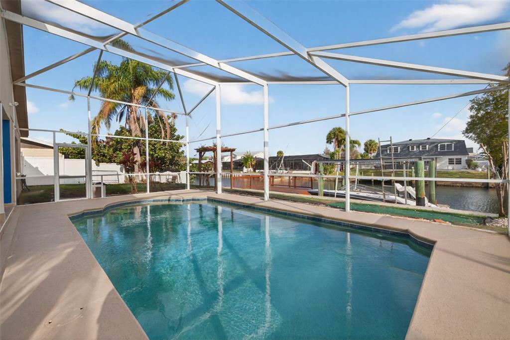 An aerial view shows a waterfront residential neighborhood with canals, swimming pools, and boat docks — 8711 BAY CREST LANE, TAMPA, FL