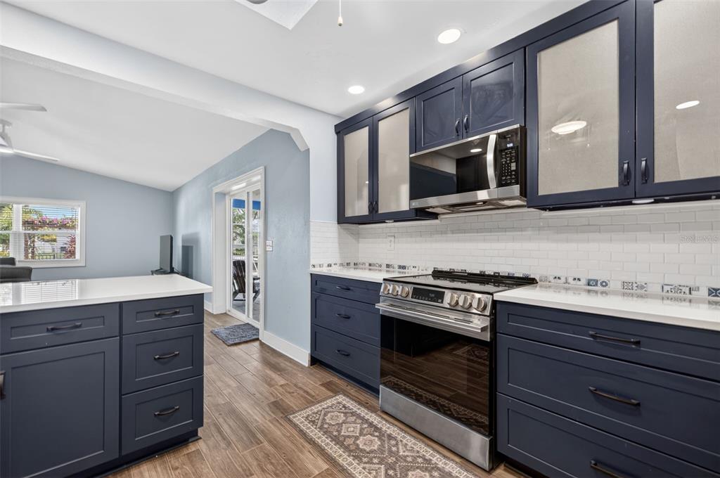 A kitchen features navy blue cabinets, white countertops, a stainless steel stove, and tile flooring — 8711 BAY CREST LANE, TAMPA, FL