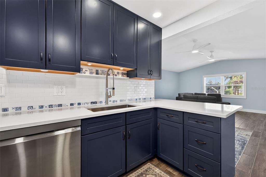 A kitchen features dark blue cabinets, white countertops, a subway tile backsplash, and stainless appliances — 8711 BAY CREST LANE, TAMPA, FL