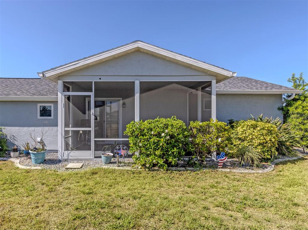The exterior of a house features a screened-in porch with a sliding glass door — 5568 KENWOOD DRIVE, NORTH PORT, FL