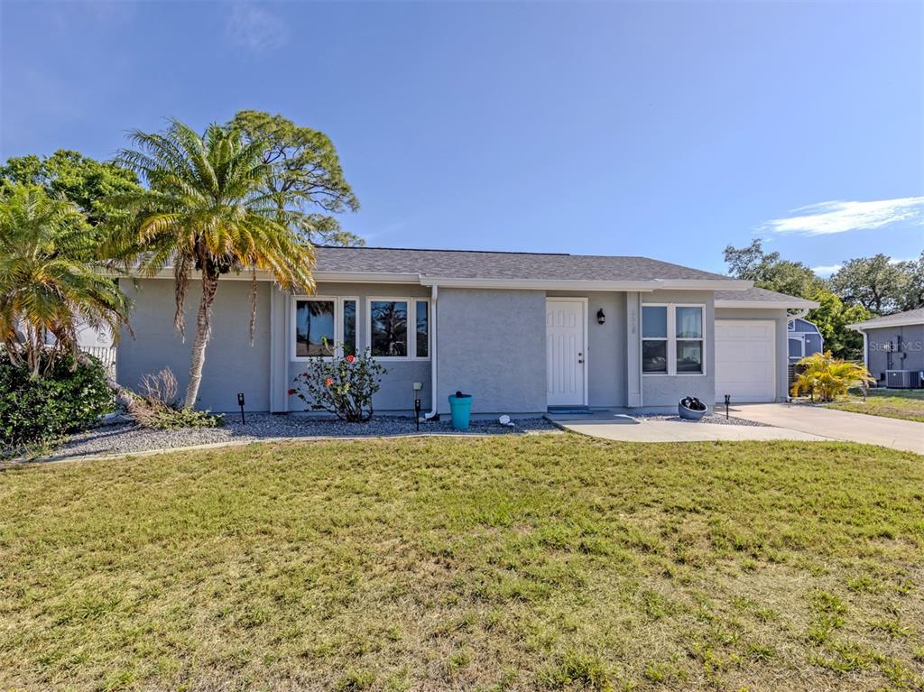 A single-story gray house with a palm tree, a front lawn, and an attached garage — 5568 KENWOOD DRIVE, NORTH PORT, FL
