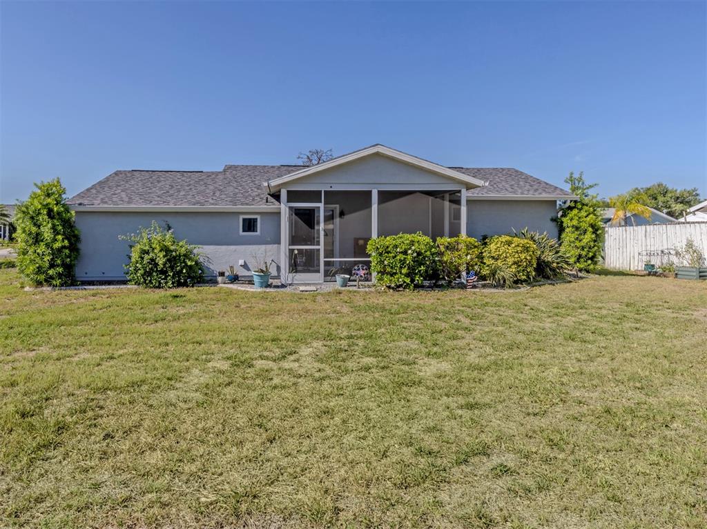 The back exterior of a single-story house features a screened-in porch and a large lawn — 5568 KENWOOD DRIVE, NORTH PORT, FL