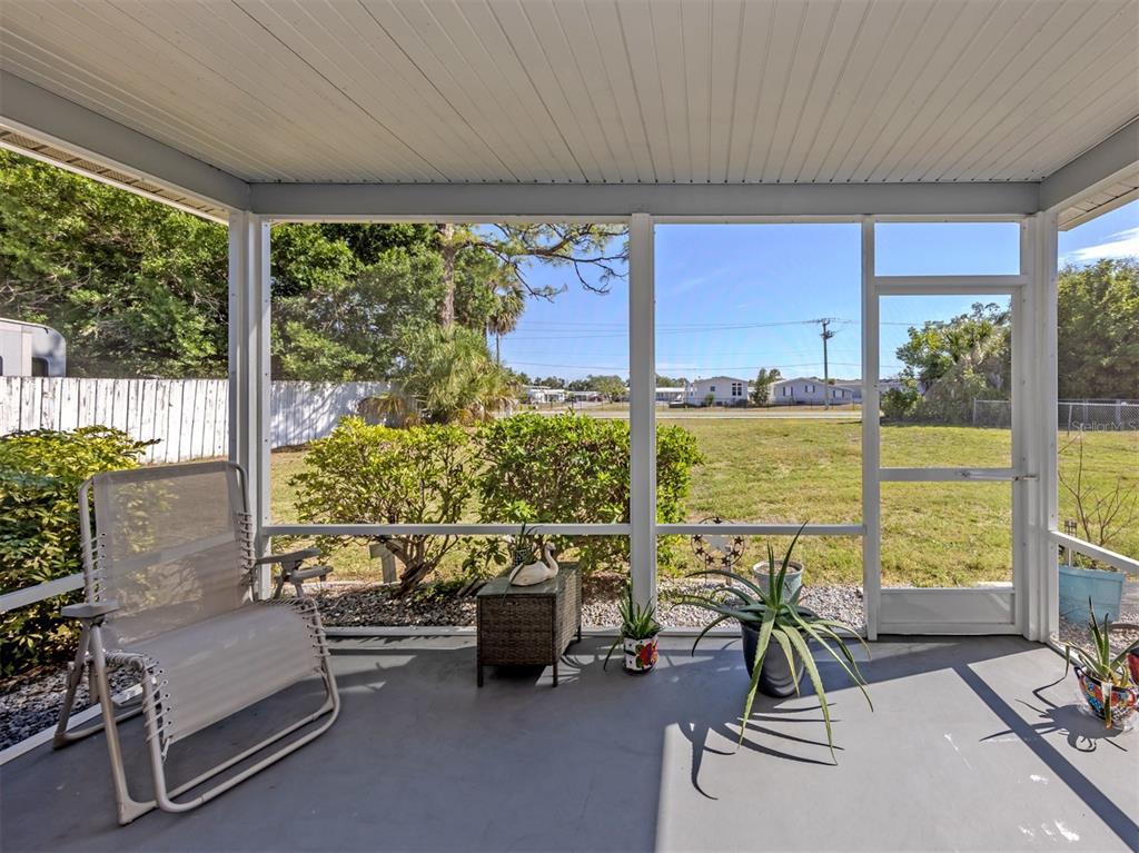 A screened-in porch features a gray floor, a white lounge chair, and a view of grass — 5568 KENWOOD DRIVE, NORTH PORT, FL