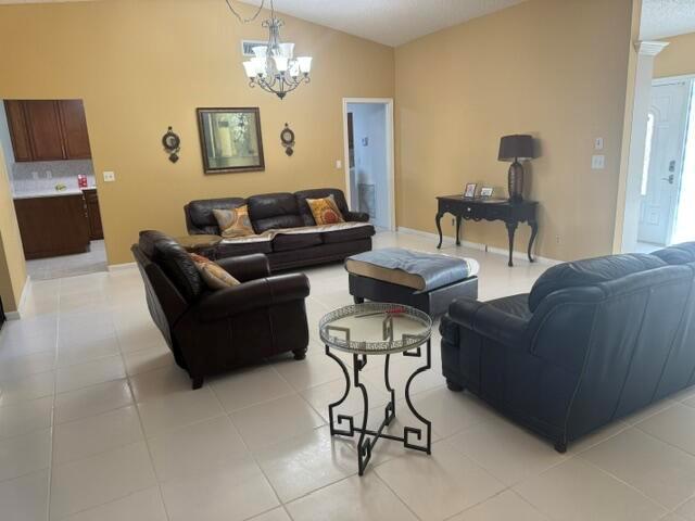 A living room features dark leather furniture, a glass-topped side table, and tile flooring — 10298 Greentrail Drive N, Boynton Beach FL 33436, BOYNTON BEACH, FL