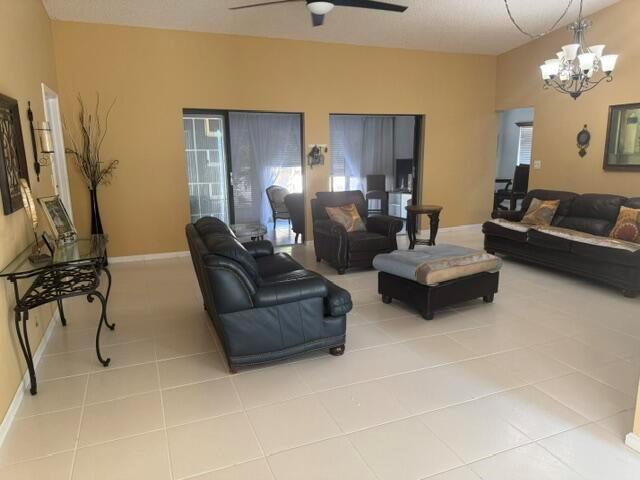 A spacious living room features tile flooring, tan walls, and dark leather furniture — 10298 Greentrail Drive N, Boynton Beach FL 33436, BOYNTON BEACH, FL