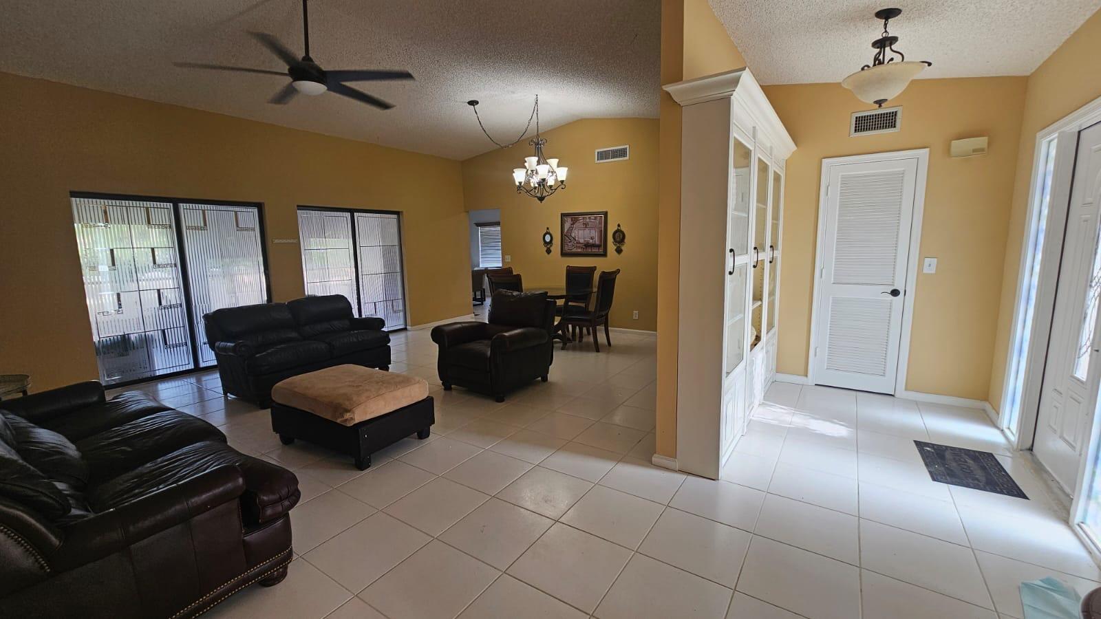 A living room with tile flooring, leather furniture, a ceiling fan, and a dining area — 10298 Greentrail Drive N, Boynton Beach FL 33436, BOYNTON BEACH, FL