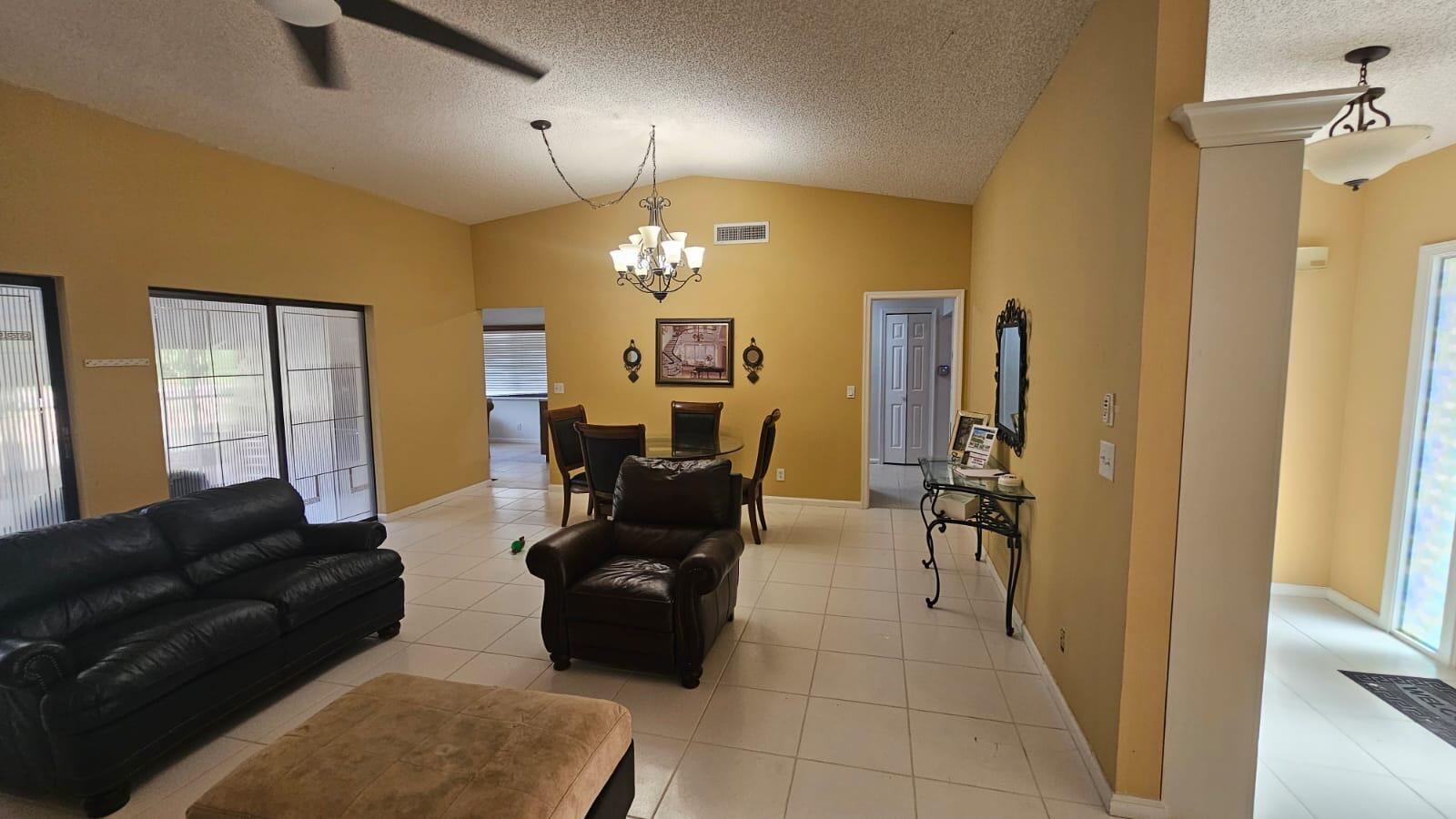 A living and dining area with yellow walls, tile flooring, and a vaulted ceiling — 10298 Greentrail Drive N, Boynton Beach FL 33436, BOYNTON BEACH, FL