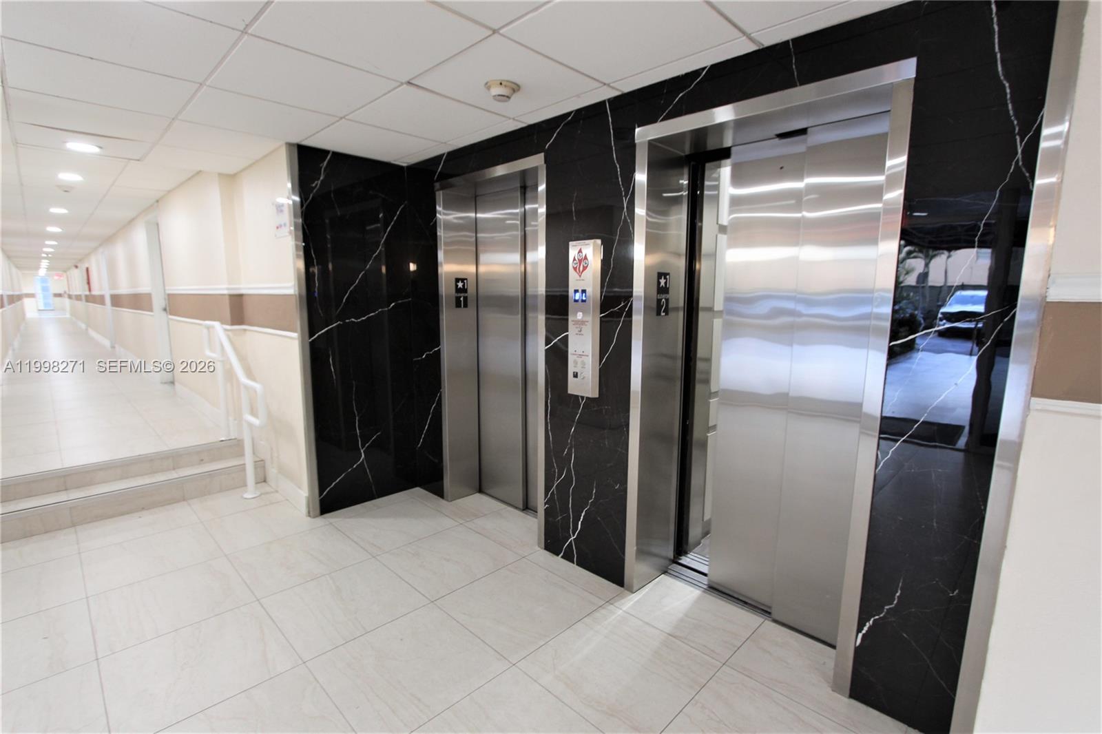 This elevator lobby features black marble-patterned walls, stainless steel doors, and a tiled floor — 4550 NW 9th St # 811E, Miami FL 33126, MIAMI, FL