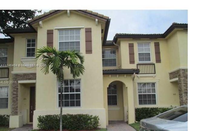 A two-story yellow stucco townhouse with stone accents and a palm tree in the front — 1420 NE 33rd Ave # 15, Homestead FL 33033, HOMESTEAD, FL