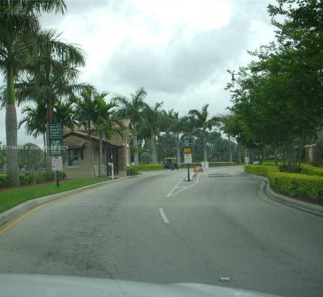A gated community entrance features a guardhouse, palm trees, and a paved road — 1420 NE 33rd Ave # 15, Homestead FL 33033, HOMESTEAD, FL