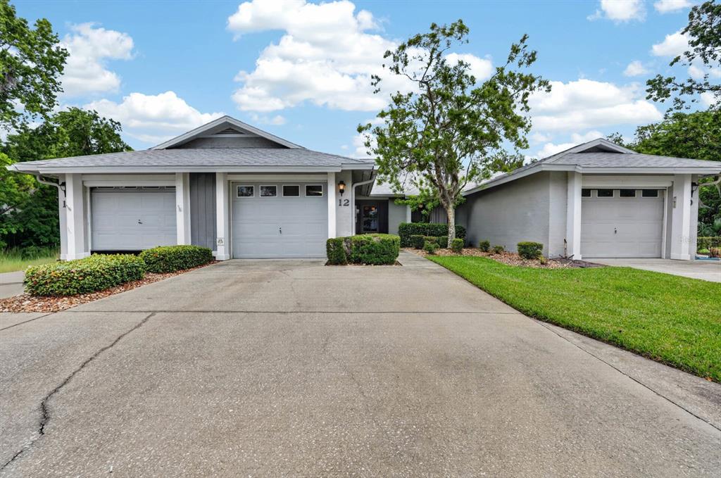 A single-story house with a three-car garage and a concrete driveway under a blue sky — 12 LAKE FOREST CIRCLE N, PALM COAST, FL