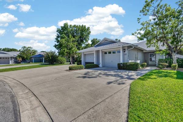 A single-story house with a two-car garage and a concrete driveway under a blue sky — 12 LAKE FOREST CIRCLE N, PALM COAST, FL