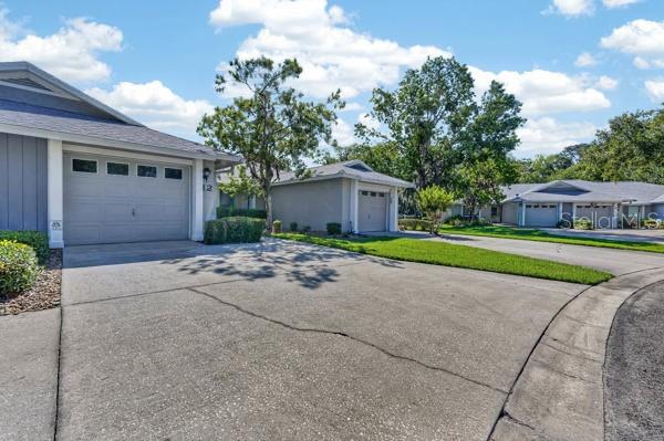 A concrete driveway leads to the garage of a single-story house under a blue sky — 12 LAKE FOREST CIRCLE N, PALM COAST, FL