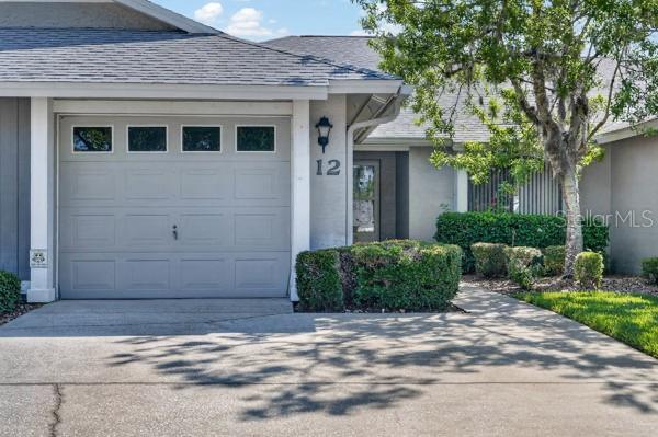A single-story residential building features a gray garage door, a front entrance, and landscaping — 12 LAKE FOREST CIRCLE N, PALM COAST, FL