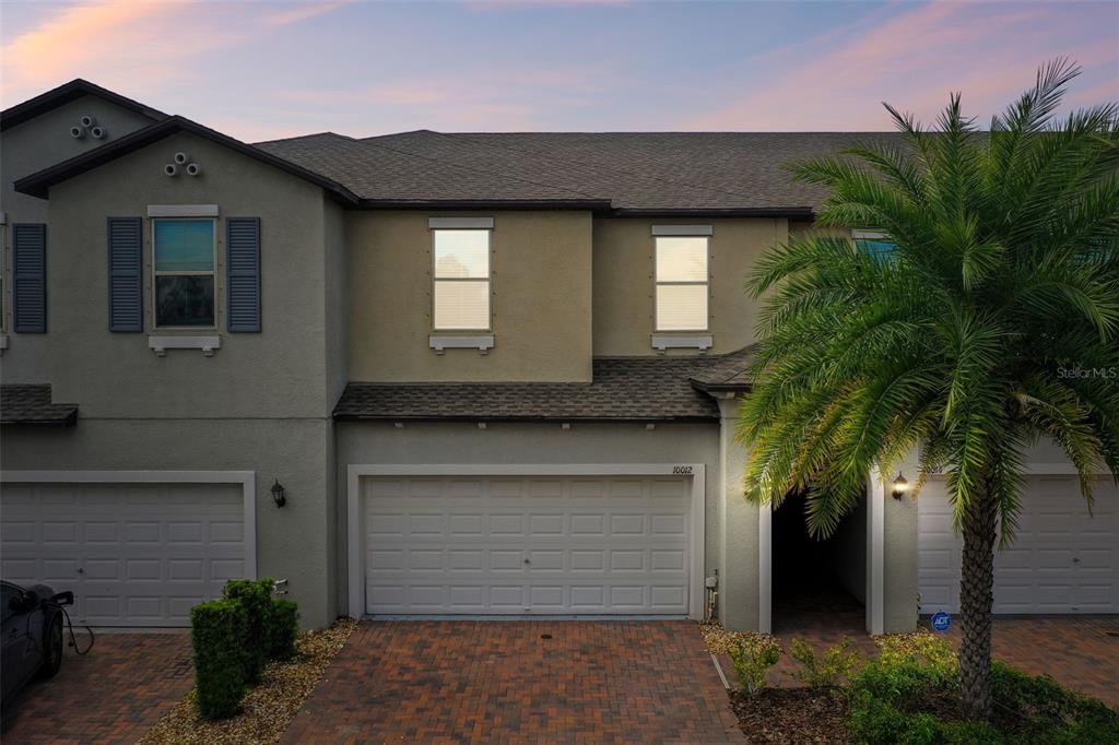 A brick pillar supports a hanging sign that reads Avesa above a landscaped flower bed — 10012 CORSO MILANO DRIVE, TAMPA, FL