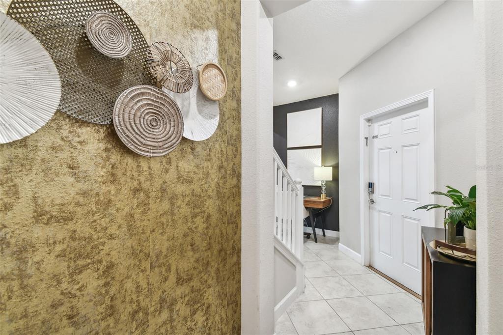 An entryway features a gold textured accent wall with circular wall art and tiled floors — 10012 CORSO MILANO DRIVE, TAMPA, FL