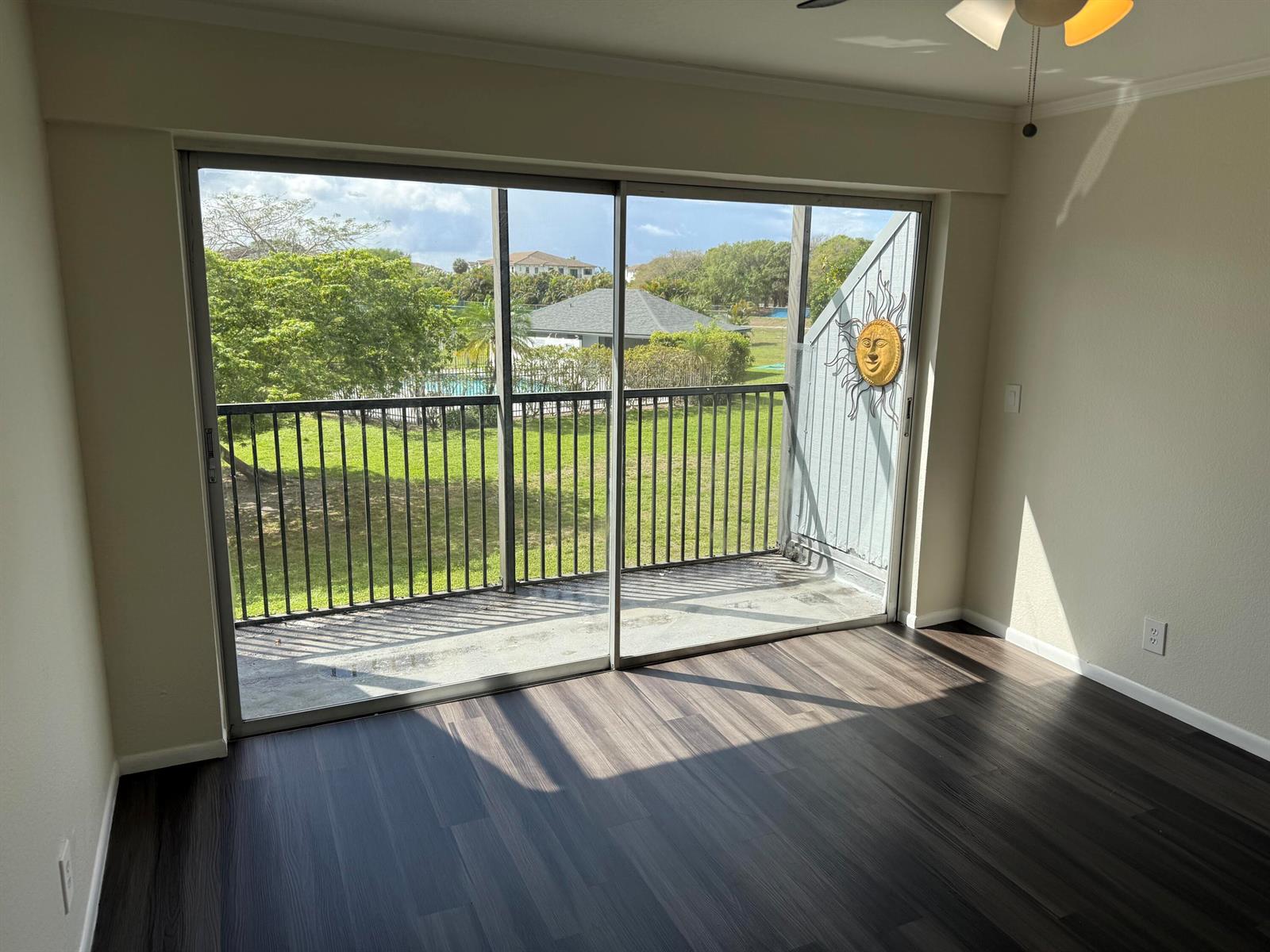 An empty room with dark wood-look flooring features a large sliding glass door to a balcony — 9500 SW 3rd Street # 222, Boca Raton FL 33428, BOCA RATON, FL