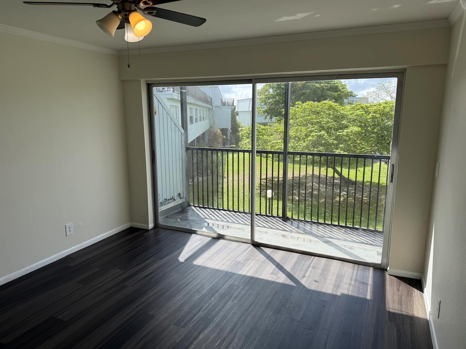 An empty room with dark wood-look flooring, a ceiling fan, and a sliding glass balcony door — 9500 SW 3rd Street # 222, Boca Raton FL 33428, BOCA RATON, FL