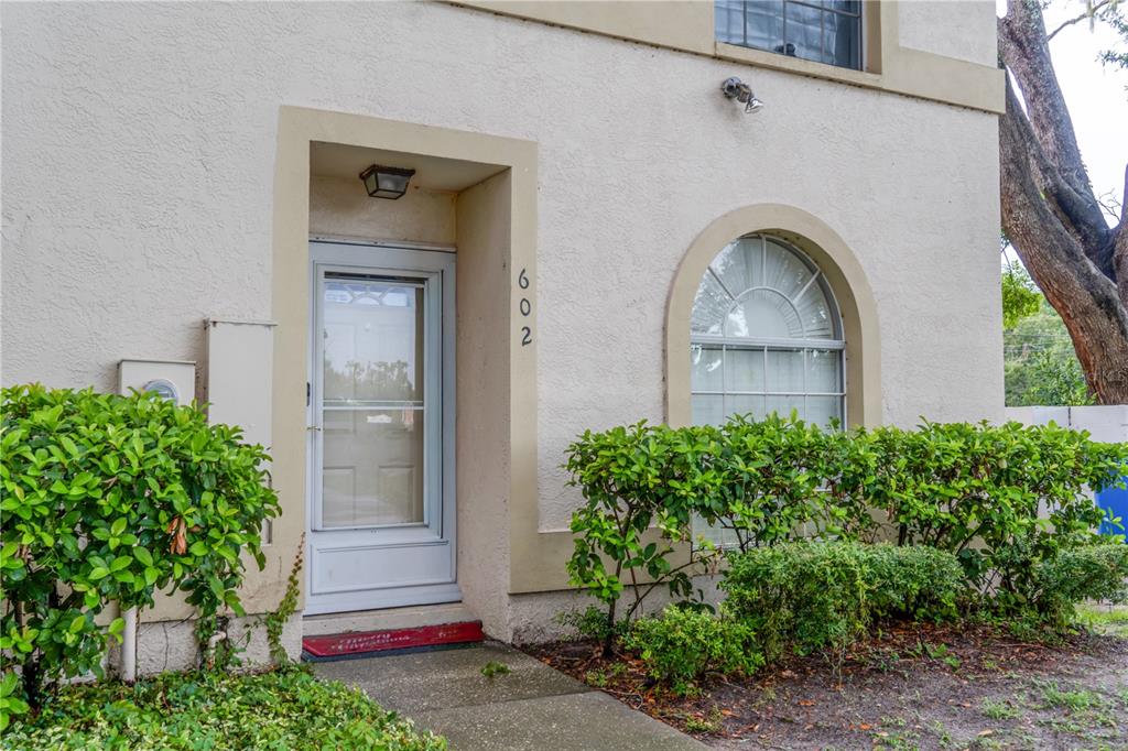 The exterior of a beige stucco building features a front door and an arched window — 602 SAINT HENRY DRIVE, BRANDON, FL