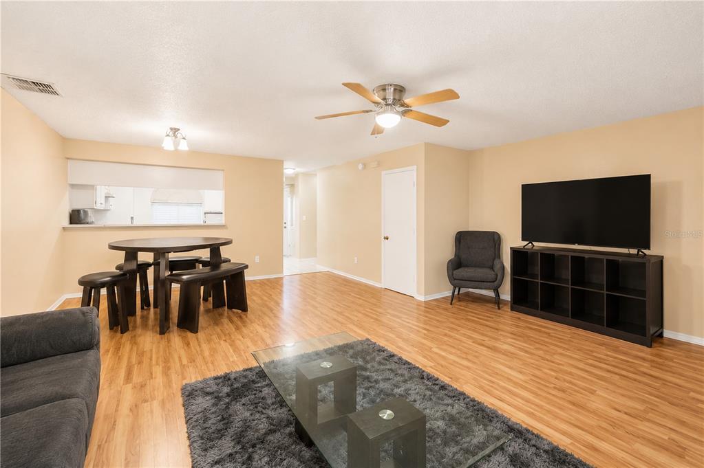 A living and dining area with wood-look flooring, a ceiling fan, and a television console — 602 SAINT HENRY DRIVE, BRANDON, FL