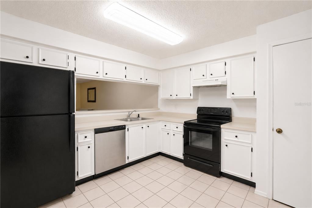 A kitchen with white cabinets, black appliances, a stainless steel dishwasher, and tiled flooring — 602 SAINT HENRY DRIVE, BRANDON, FL