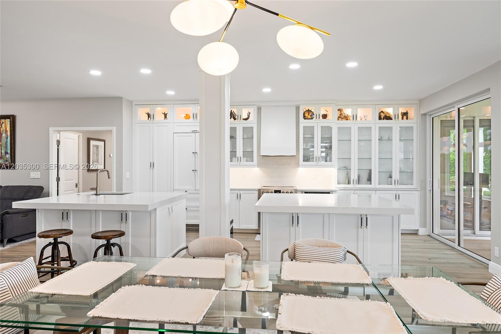 A bright kitchen features white cabinetry, two islands, and a dining table in the foreground — 316 Spyglass Way, Jupiter FL 33477, JUPITER, FL