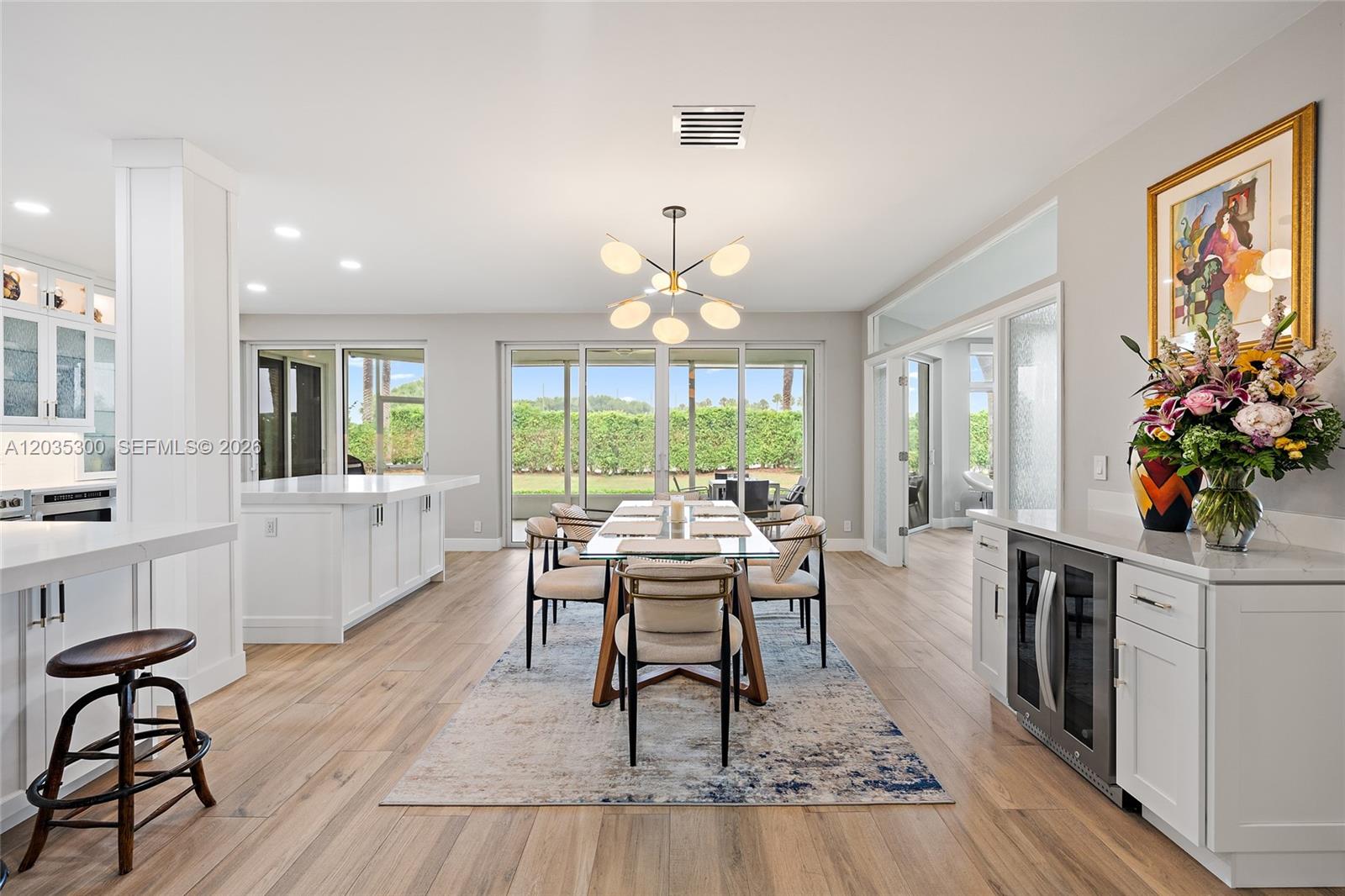 A modern dining area features a glass table, contemporary chandelier, and light wood flooring — 316 Spyglass Way, Jupiter FL 33477, JUPITER, FL