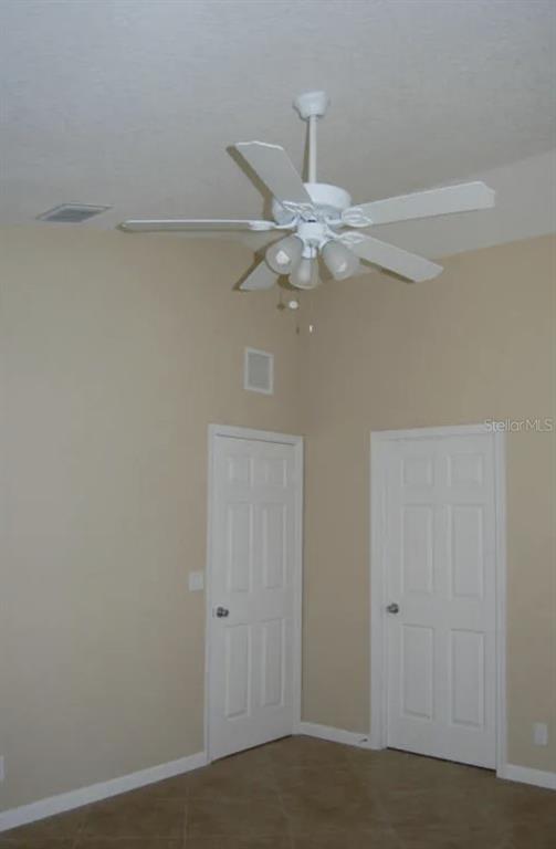 A room with beige walls, tile flooring, two white doors, and a ceiling fan — 926 SW 11TH TERRACE, DELRAY BEACH, FL