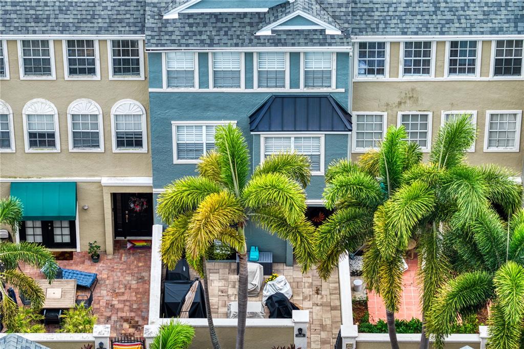 An aerial view shows the exterior of a multi-story townhouse with palm trees and patios — 1425 HARBOUR WALK ROAD, TAMPA, FL