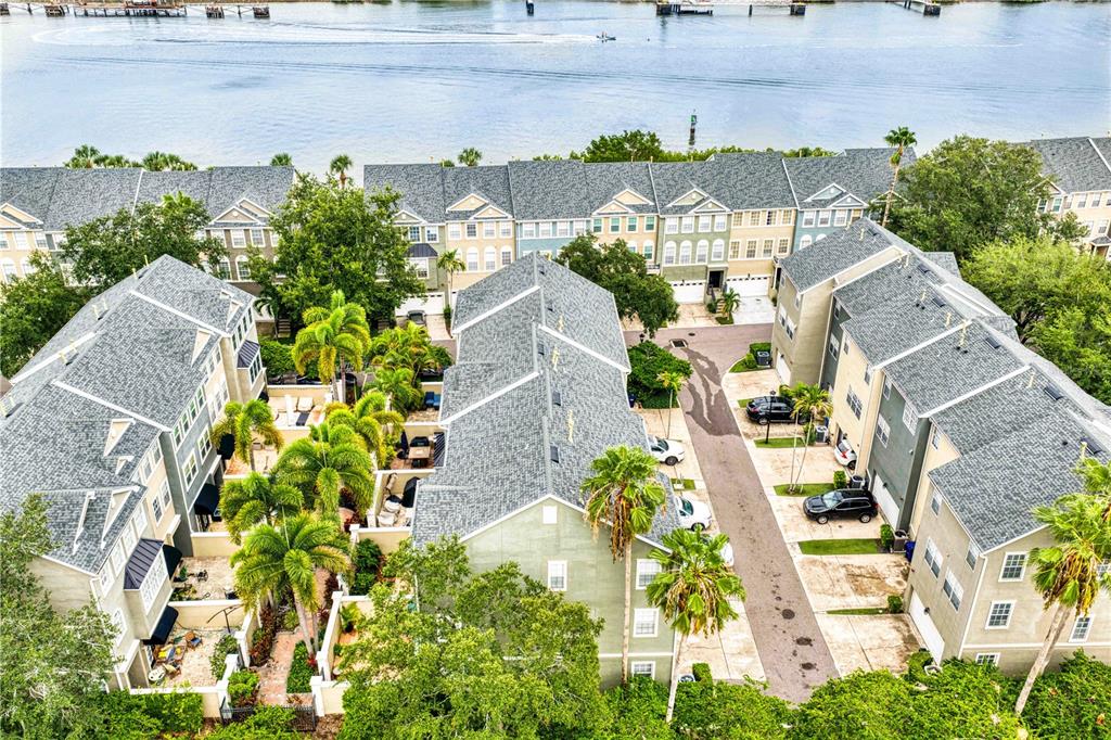 An aerial view shows several multi-story townhomes with gray roofs near a body of water — 1425 HARBOUR WALK ROAD, TAMPA, FL