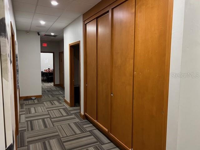 A hallway with patterned carpet, wood-paneled walls, and multiple doorways leading to other rooms — 4965 SW 91ST TERRACE, GAINESVILLE, FL