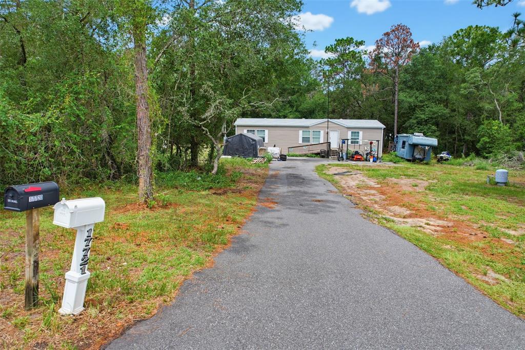 A single-story manufactured home sits at the end of a long asphalt driveway — 17721 DRAYTON STREET, SPRING HILL, FL