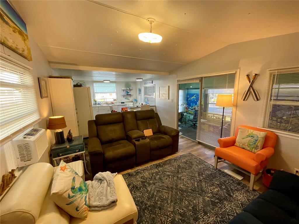 A living room features a brown reclining sofa, an orange armchair, and an open kitchen — 6580 SEMINOLE BOULEVARD UNIT 510, SEMINOLE, FL