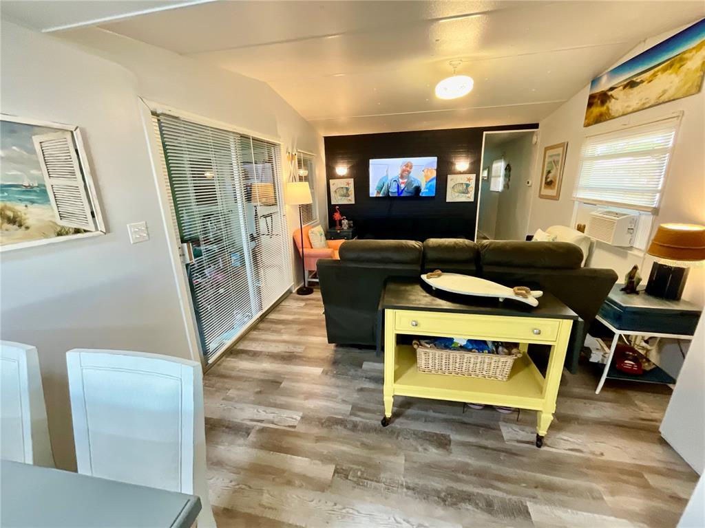 A living room features wood-look flooring, a dark accent wall with a television, and furniture — 6580 SEMINOLE BOULEVARD UNIT 510, SEMINOLE, FL