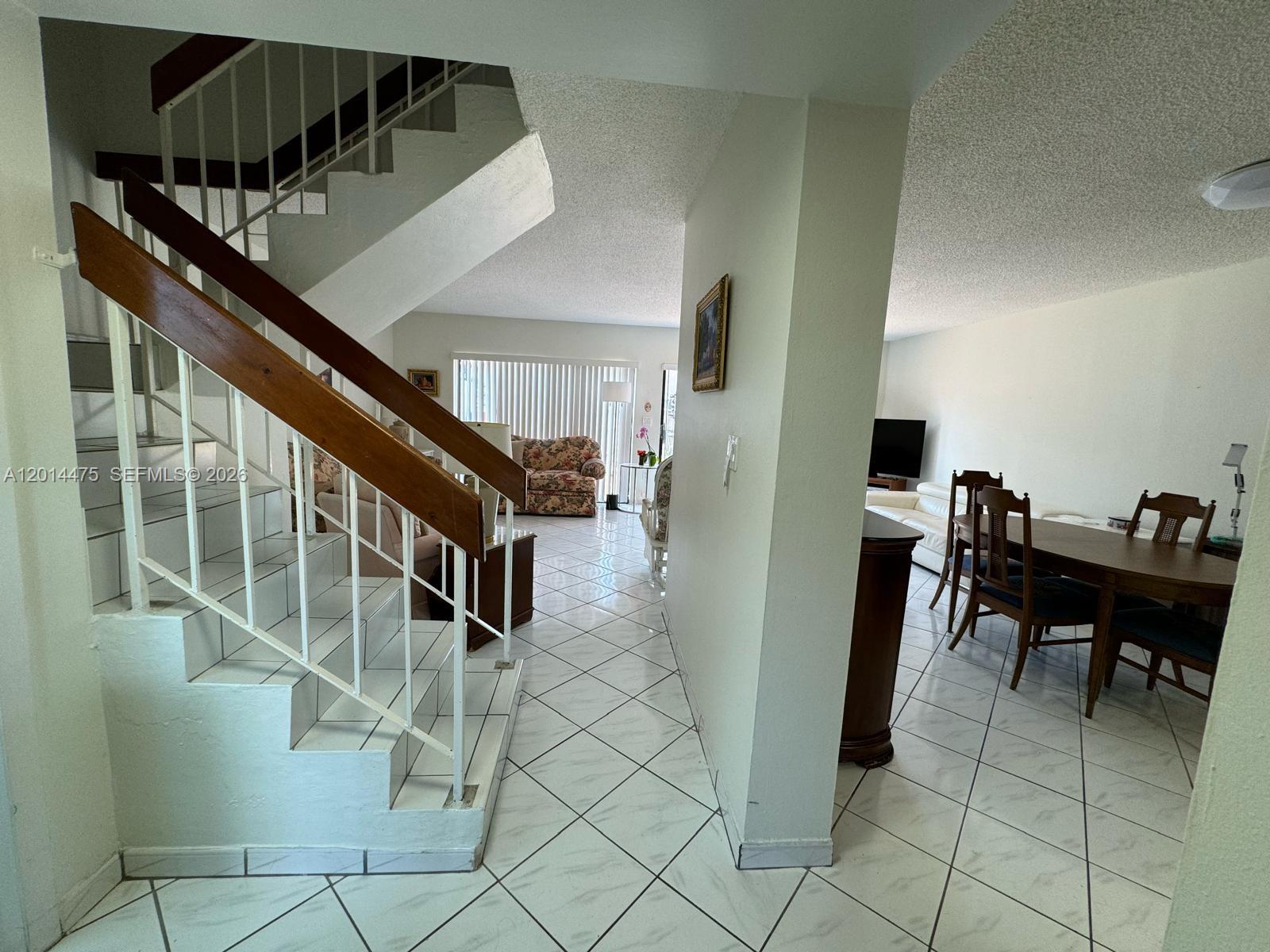 A staircase with white risers and a wooden handrail leads to an open-concept living area — 3817 SW 82nd Ave # 46, Miami FL 33155, MIAMI, FL