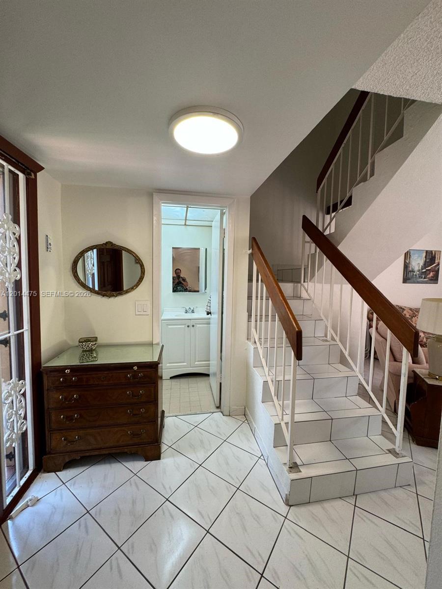 An entryway features a tiled floor, a wooden chest of drawers, and a staircase — 3817 SW 82nd Ave # 46, Miami FL 33155, MIAMI, FL