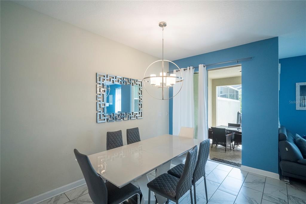A dining room features a modern chandelier, a mirrored wall art piece, and tiled floors — 436 OCEAN COURSE AVENUE, DAVENPORT, FL
