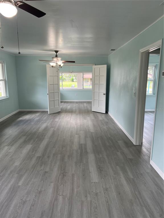 A living room with light blue walls, gray wood-look flooring, and white French doors — 860 LUSK PLACE, BARTOW, FL