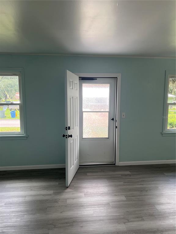 A room with light blue walls, gray wood-look flooring, two windows, and an open door — 860 LUSK PLACE, BARTOW, FL