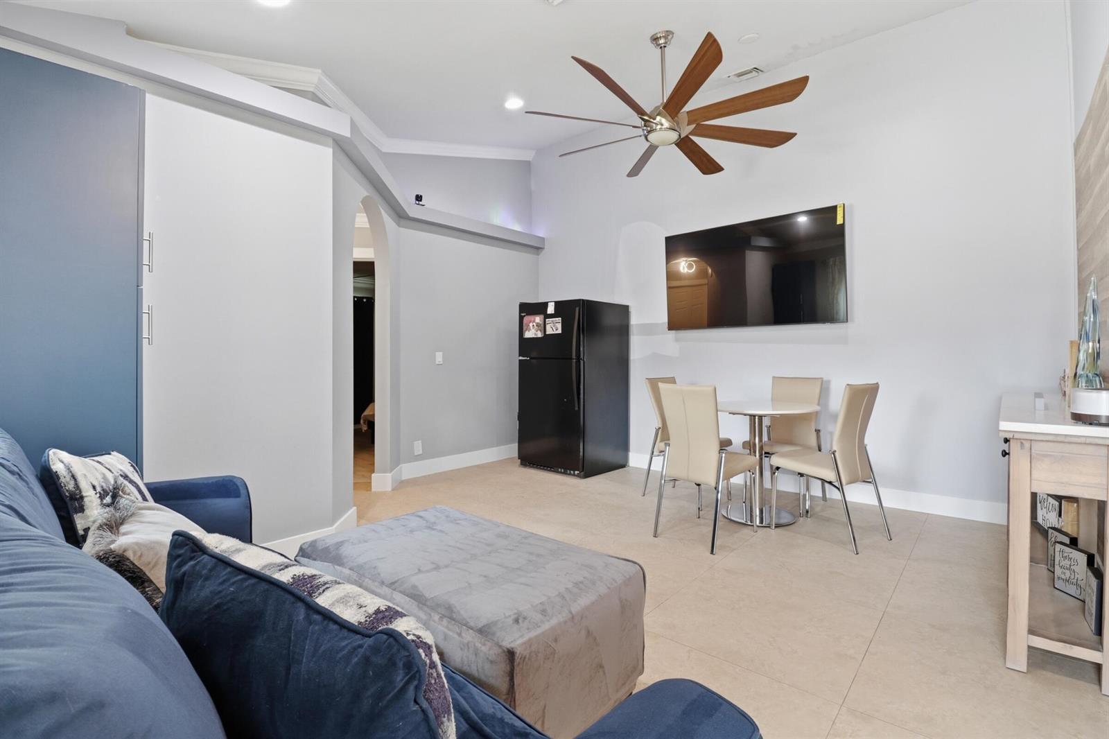 A living and dining area features a blue sofa, a black refrigerator, and a television — 1424 Primrose Lane, Wellington FL 33414, WELLINGTON, FL