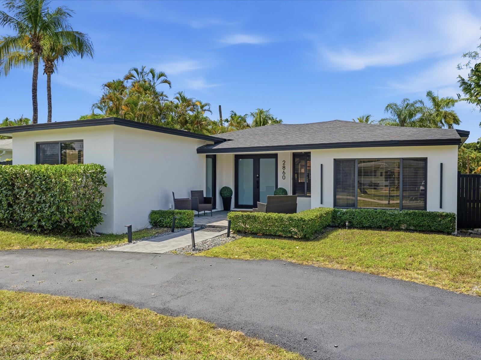A single-story house with white stucco walls, a dark roof, and a paved walkway entrance — 2860 Monroe Street, Hollywood FL 33020, HOLLYWOOD, FL