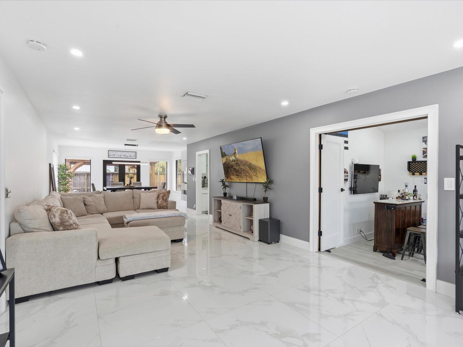 A living room with a large sectional sofa, white marble floors, and an adjacent bar — 2860 Monroe Street, Hollywood FL 33020, HOLLYWOOD, FL