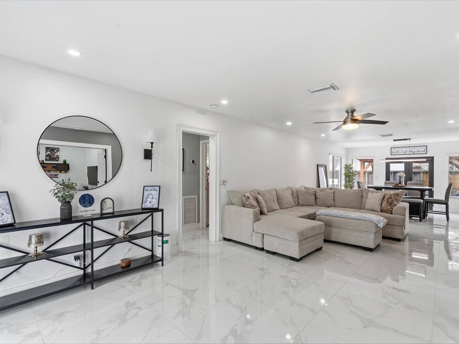 A bright living room features white marble-look tile floors, a sectional sofa, and a console table — 2860 Monroe Street, Hollywood FL 33020, HOLLYWOOD, FL