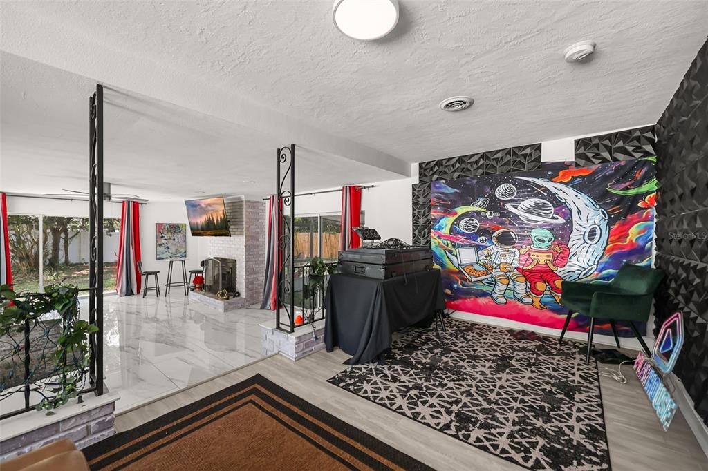 A living area features a DJ setup, a space-themed tapestry, and a white brick fireplace — 2909 HARGILL DRIVE, ORLANDO, FL