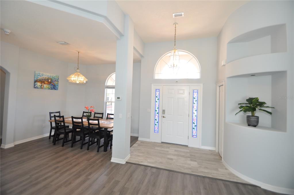 A dining area and entryway feature light blue walls, wood-look flooring, and a decorative arched window — 16 CEDARWOOD COURT, PALM COAST, FL