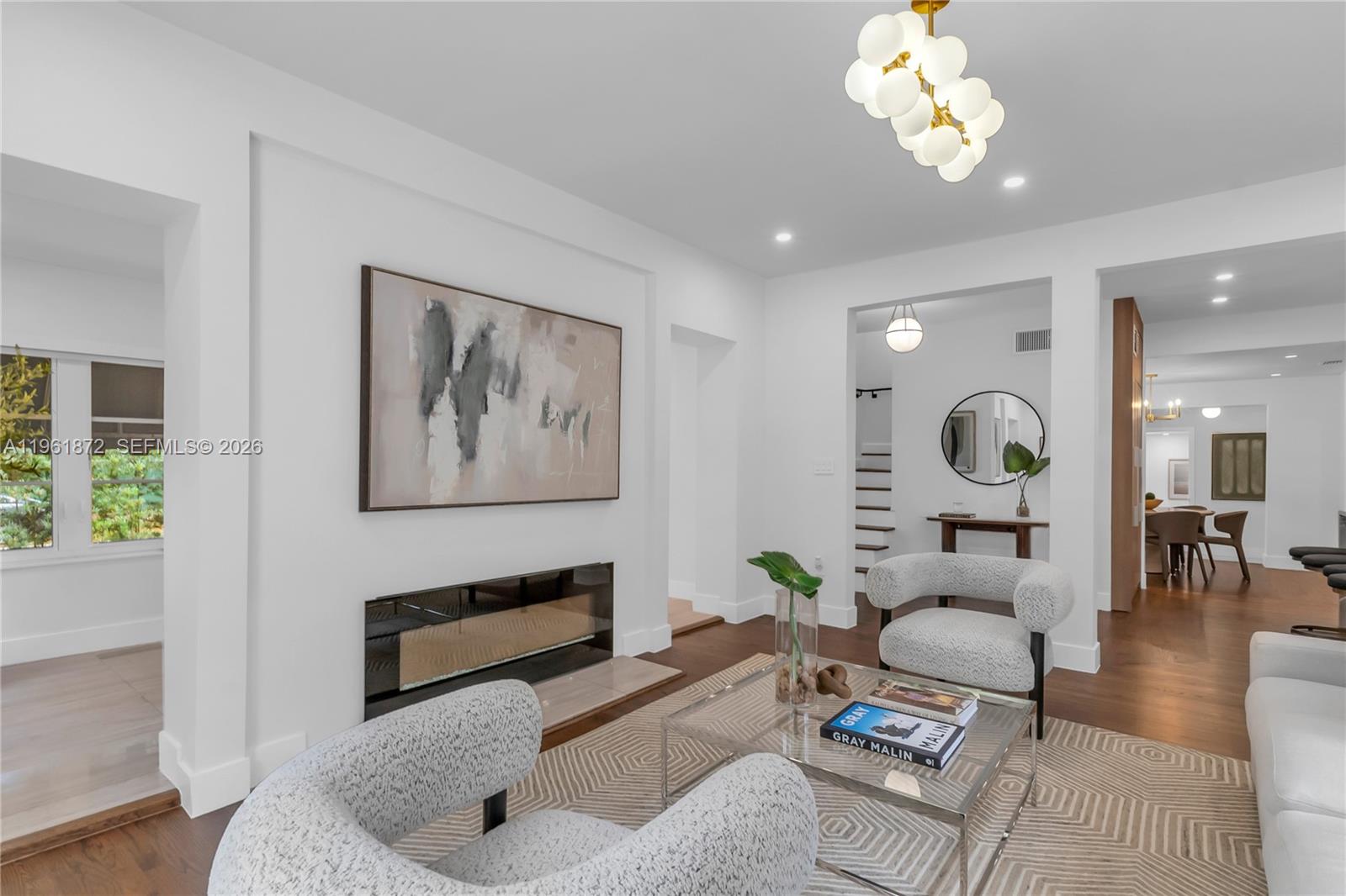 A modern living room features a fireplace, two textured armchairs, and a glass coffee table — 1222 Cortez St, Coral Gables FL 33134, CORAL GABLES, FL