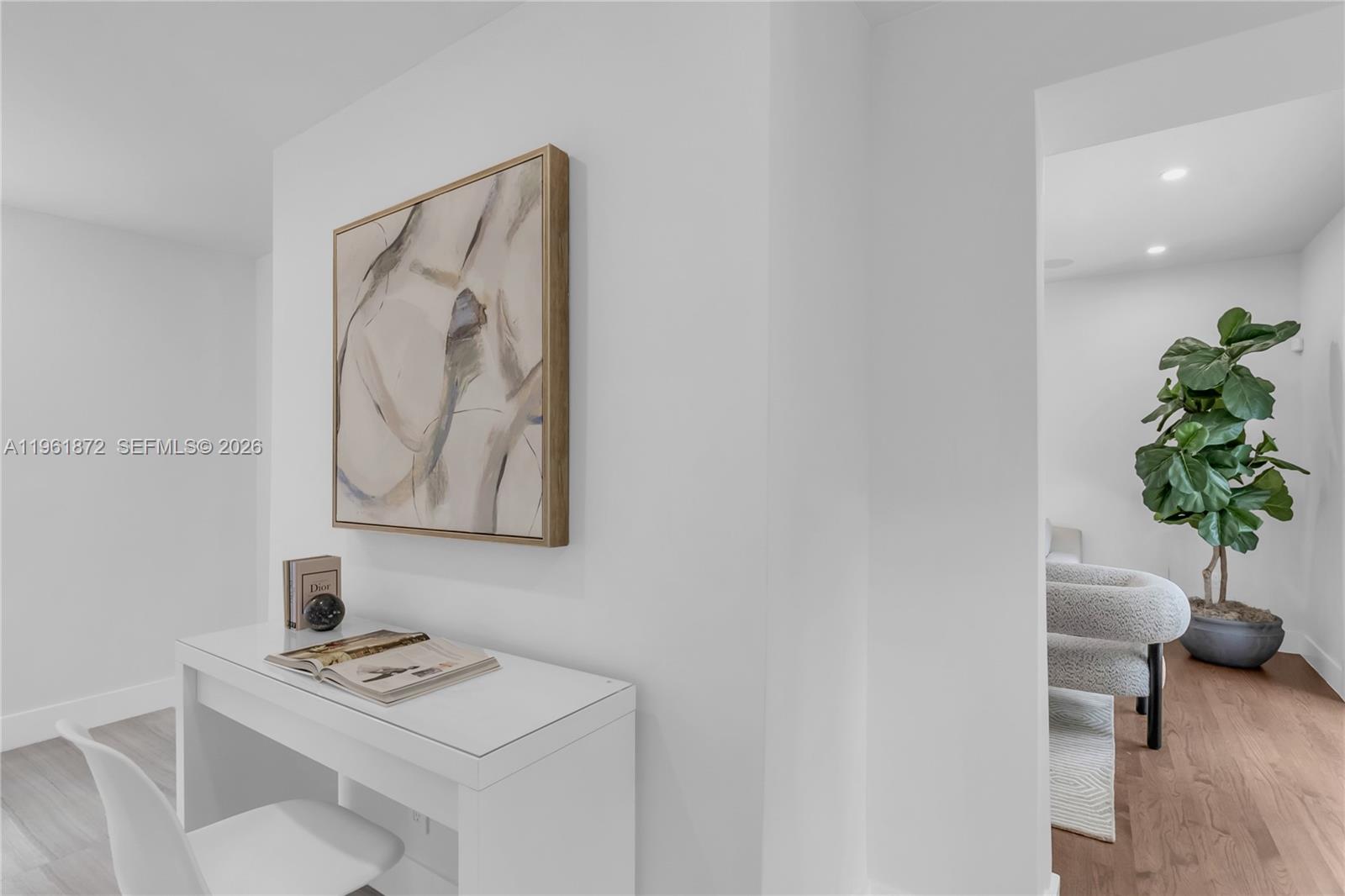 A white desk with a book and abstract art sits beside a doorway to a room — 1222 Cortez St, Coral Gables FL 33134, CORAL GABLES, FL