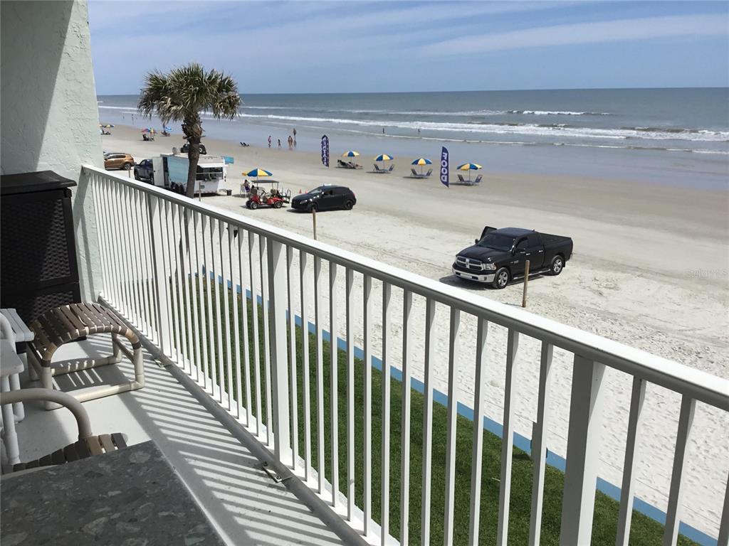 A balcony overlooks a sandy beach with parked vehicles and the ocean — 1571 S ATLANTIC AVENUE UNIT 209, NEW SMYRNA BEACH, FL