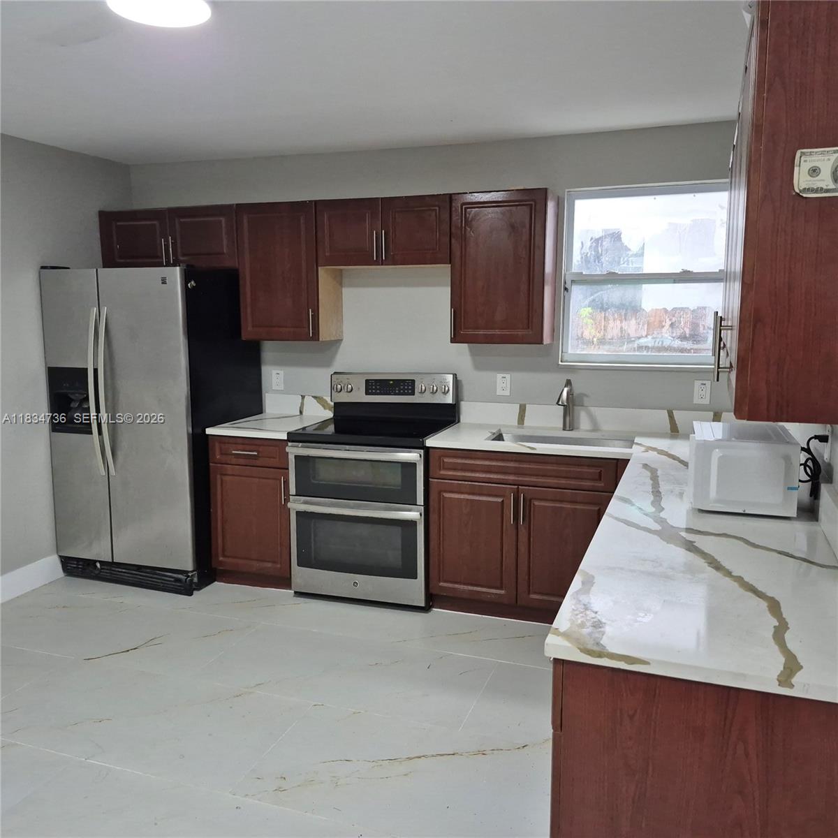 A kitchen features dark wood cabinets, stainless steel appliances, and white marble-patterned countertops — 1770 NW 44th St, Miami FL 33142, MIAMI, FL